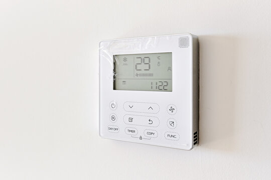 Close up of modern wall-mounted digital thermostat on white wall background. Smart home , modern technology