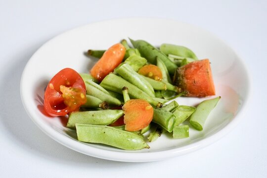 Small portion of organic vegetable food waste trashes on white plate isolated on horizontal white background.