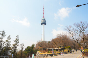 Obraz premium Scenic view of N Seoul Tower and a historic stone fortress wall framed by bare trees in Namsan Park