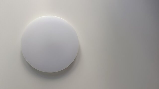 Minimalist round white led ceiling light fixture mounted on plain pastel surface in modern ascetic style interior
