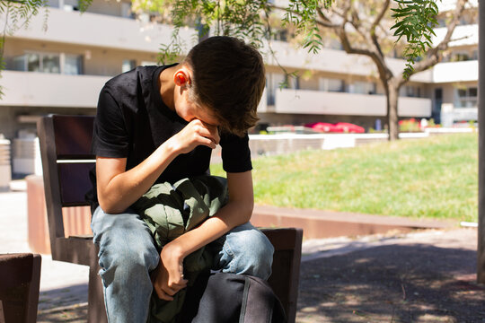 Lonely teenager sitting on the bench outdoors