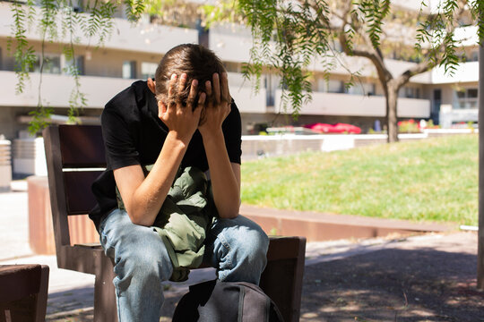 Lonely teenager sitting on the bench outdoors