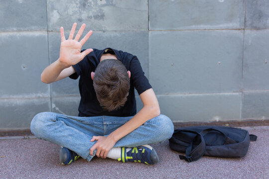 Lonely teenager showing a stop sign sitting on the floor