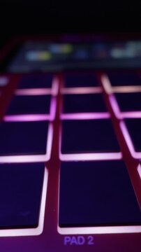 Close up of drum machine pads lighting up with colorful LEDs in a dark studio. Concept of electronic music creation, beatmaking workflow and modern audio technology.
