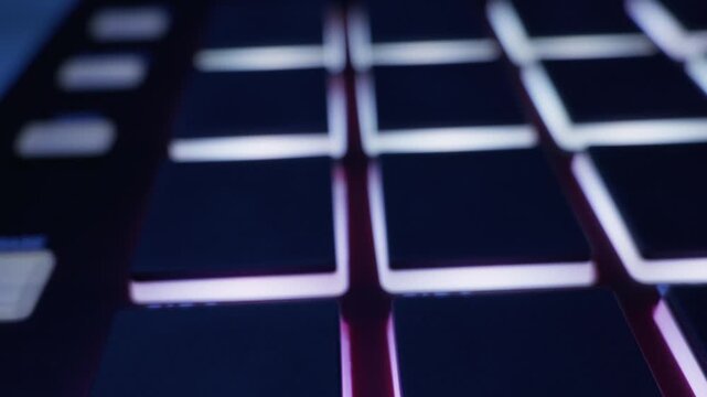 Smooth camera movement over glowing rubber pads of a professional music production sampler. Concept of creating electronic beats, modern audio technology, and digital studio workflow.