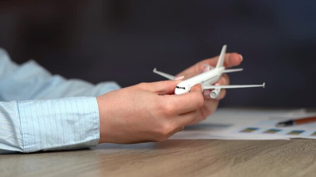 A woman examines a passenger plane in her hands. Concept of air transport and travel. Buy plane tickets. Travel booking. Global destinations