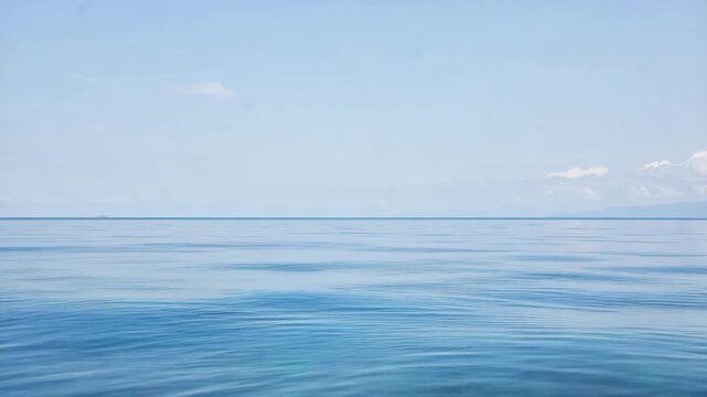 A serene seaside view with gentle waves and a clear blue sky.