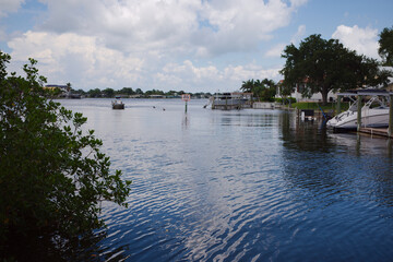 Fototapeta premium Calm Residential Waterfront With Boats, Private Docks and Cloudy Sky Over a Tranquil Bay Crisp Park in St. Petersburg, FL conveying peaceful coastal living, leisure boating and relaxed summer atmosphe
