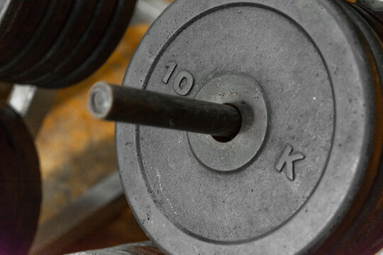 Close-up of a 10 kg black weight plate loaded onto an Olympic barbell in a gym.