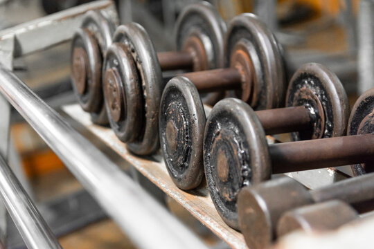 Close-up of metallic and chrome dumbbells arranged on a gym rack.