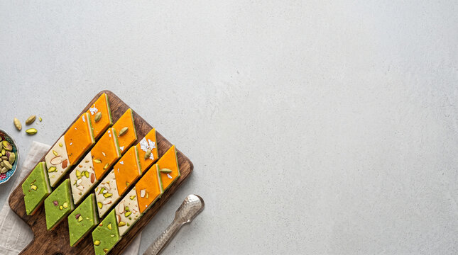 Tricolor indian barfi sweets flat lay on wooden board