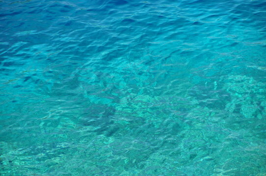Crystal clear turquoise ocean water viewed from above. Abstract tropical sea background with vibrant blue and aqua tones.
