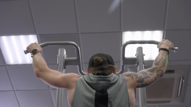 Man performs pull ups in gym to build strength and improve fitness during training session