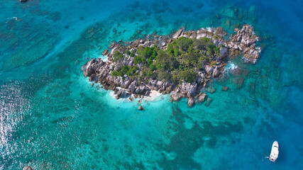 Fototapeta premium Breathtaking drone shot of Cocos Island, Seychelles, showcasing an exotic tropical paradise with lush green trees, giant granite boulders, and crystal-clear turquoise waters.