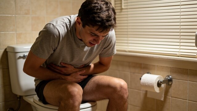 Young man suffering from diarrhea on toilet bowl at home