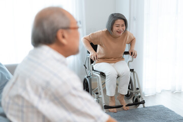Obraz premium Two elderly people are sitting on a couch in their living room. They are smiling and enjoying a conversation. The sun is shining through the window.