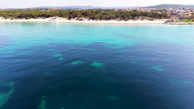 Aerial fixed slow motion view of Maria Pia Beach showing turquoise water sandy coastline and Mediterranean shoreline in calm summer conditions.
