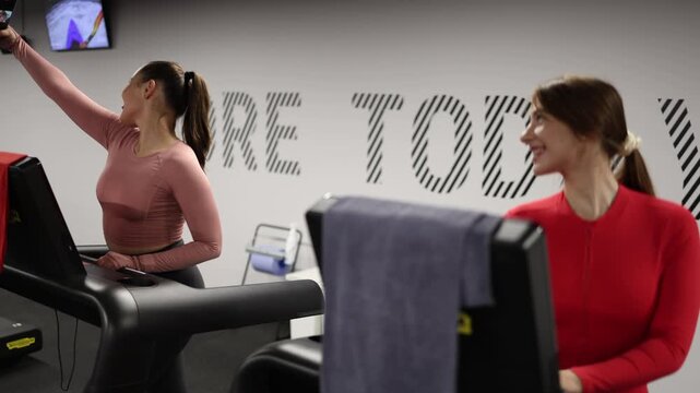 Women interrupt their treadmill workout to take selfies and create social media content choosing online attention over exercise focus and fitness progress