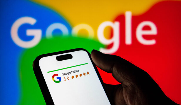 Closeup of a hand holding a smartphone displaying a perfect 50 google rating against a colorful google logo background