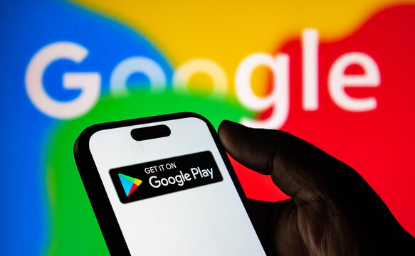 Closeup of a person holding a smartphone displaying the google play store logo against a colorful google background