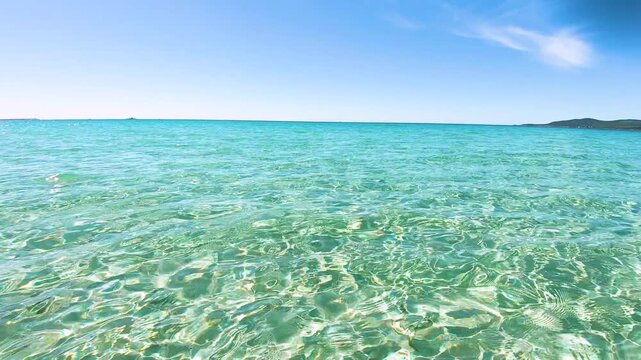 Crystal clear turquoise water viewed at sea level on a sunny day in Sardinia showing transparent Mediterranean water and natural coastal scenery in calm conditions.