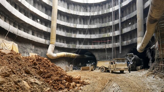 View of a deep circular underground construction shaft with heavy machinery, ventilation pipes, and reinforced concrete walls at a subway site in Istanbul, Istanbul, Turkiye.