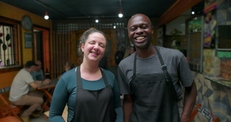 Obraz premium Smiling small business café staff standing together inside neighborhood restaurant conveying teamwork warmth hospitality trust shared effort pride community connection