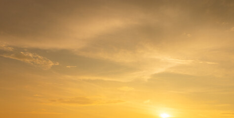 Fototapeta premium Beautiful Golden Sunset Sky with Soft Clouds,A stunning view of a serene sky during sunset, featuring a soft gradient of blue fading into golden yellow light with gentle, wispy clouds scattered.