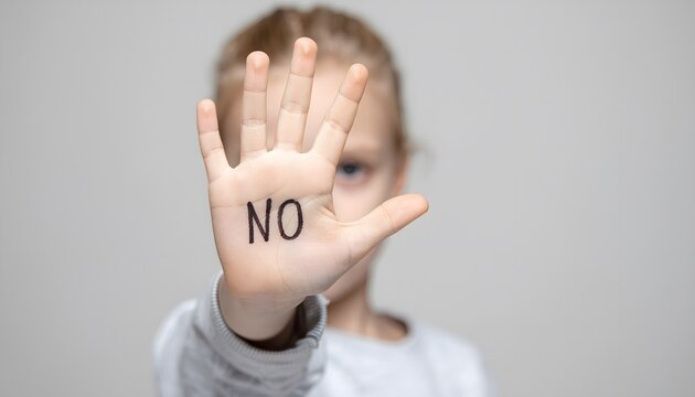 A blurred young child holding up an open hand to the camera with the word NO written on the palm, symbolizing child abuse prevention, domestic violence awareness, and social protection