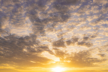 Fototapeta premium Golden Sunset Sky with Dramatic Clouds,A breathtaking view of a vibrant sunset casting a warm golden glow across a textured, cloud-filled sky at dusk.