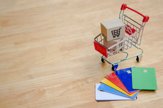 Shopping cart with cardboard box and credit card on wood table, online shopping concept, payment