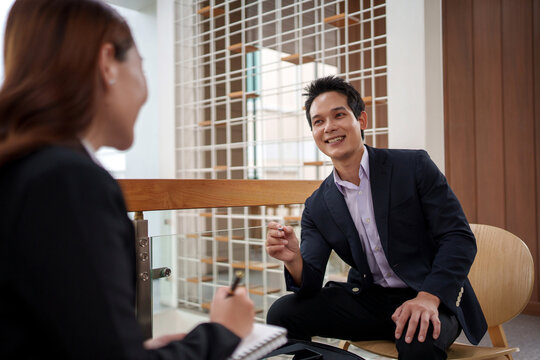 Happy businessman answering questions during a job interview with a female recruiter taking notes