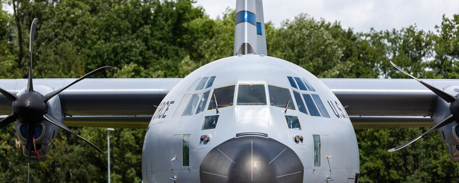 Front view air Force military cargo aircraft fuselage cockpit window turboprop engines parked airfield. Strategic aviation airpower logistics mobility defense readiness global operational capability