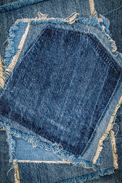 Denim patches sewn together in various shades of blue on fabric canvas in a craft setting during daytime