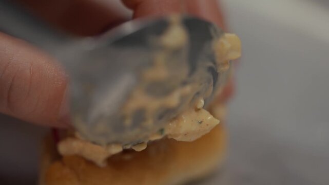 Close-up of peanut butter being spread on bread with a spoon