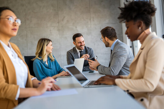 Multicultural professional businesspeople working together on research plan in boardroom.