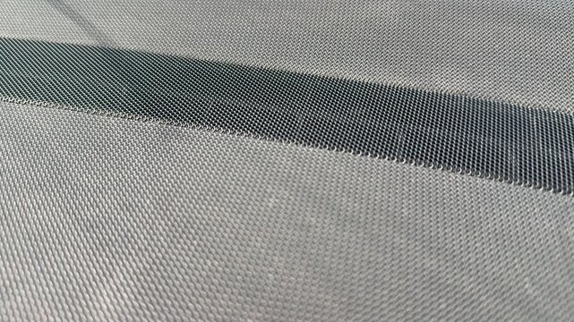 Close-up of perforated speaker grille fabric on a car dashboard, textured vehicle interior surface, automotive audio system, interior detail.