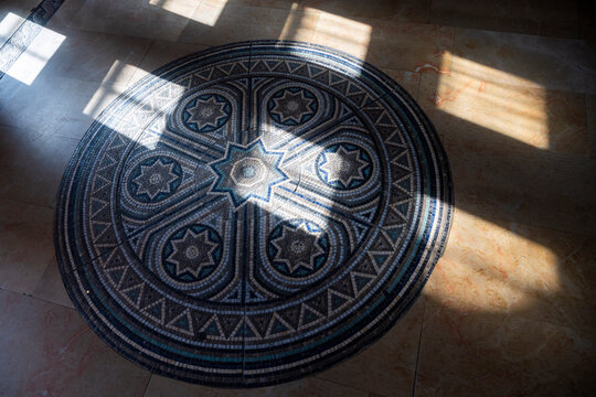  Jerusalem, Israel, June 13, 2026. High angle view of a beautiful circular mosaic pattern on a stone floor with shadows and sunlight creating a geometric contrast.
International YMCA