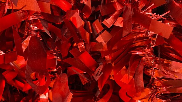 The red abstract background with metallic ribbons, decorative pieces, and reflective textures creates a dynamic, energetic, and modern impression.