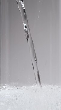 グラスに注がれる爽快な炭酸水。湧き上がる気泡と真っ白な泡の縦位置4K動画素材