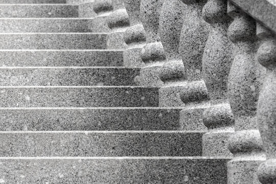 Granite steps ascend beside a carved balustrade, captured in black-and-white to emphasize texture, rhythm and classical architectural detail. Strong lines and repetition create a timeless, formal mood