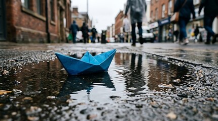 Obraz premium Paper boat floating in puddle on a city street on a rainy day.