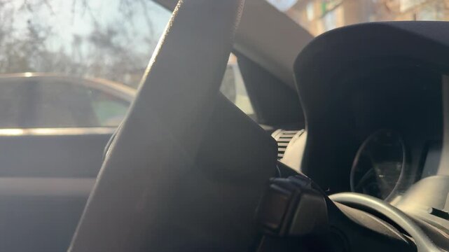 Seat belt strap is pulled and slides across the front seat inside a car, restraint movement, passenger safety, automotive interior operation.