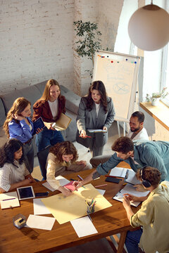 Startup team brainstorming product ideas from top view in office. Concept of collaborative planning, creative workflow, business strategy, design sprint, team productivity.