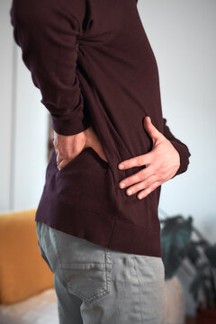 Man with hip, back, spine and sciatica pain at home.