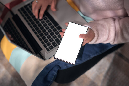 Woman using smartphone and laptop at home &ndash; remote work, online communication and digital lifestyle.