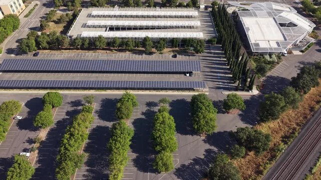 Drone footage flying over solar panels and parking lots towards modern office building.