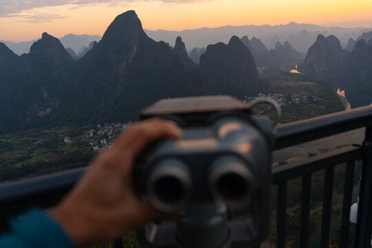 Person adjusting pair of binoculars at viewpoint in China 