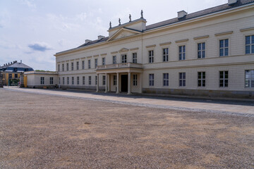 The facade of a historic white palace with multiple windows set against a gravel forecourt in Herrenhausen Gardens, Hannover, Germany. © steheap