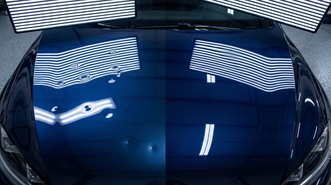 Technician using light board to identify dent on blue car hood. Paintless dent repair process showing reflection lines for precision bodywork. Automotive collision restoration service.